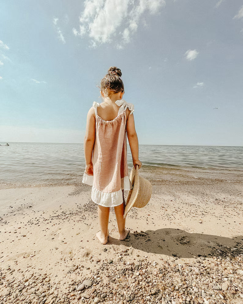 Meisje draagt zomerse jurk tijdens wandeling op het strand