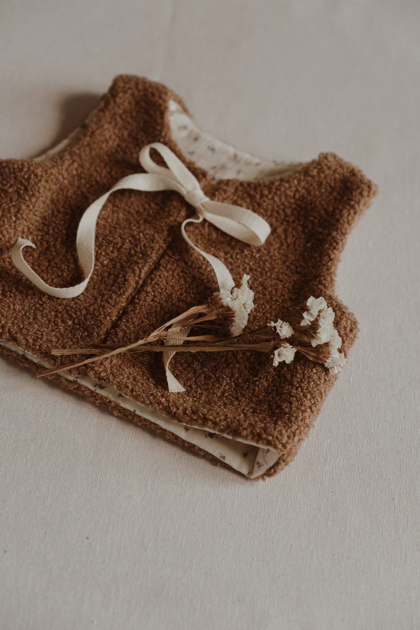 Warme bruine baby bodywarmer met strikdetail en minimalistisch design