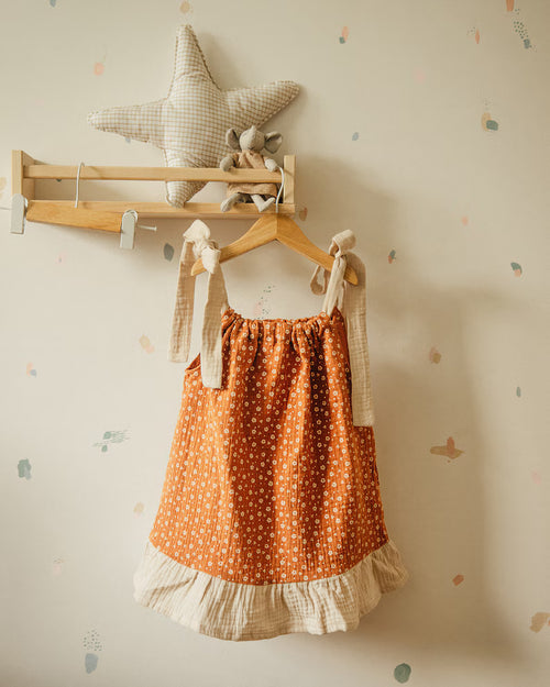 Zomerse oranje meisjesjurk met print en lichte stof aan hanger