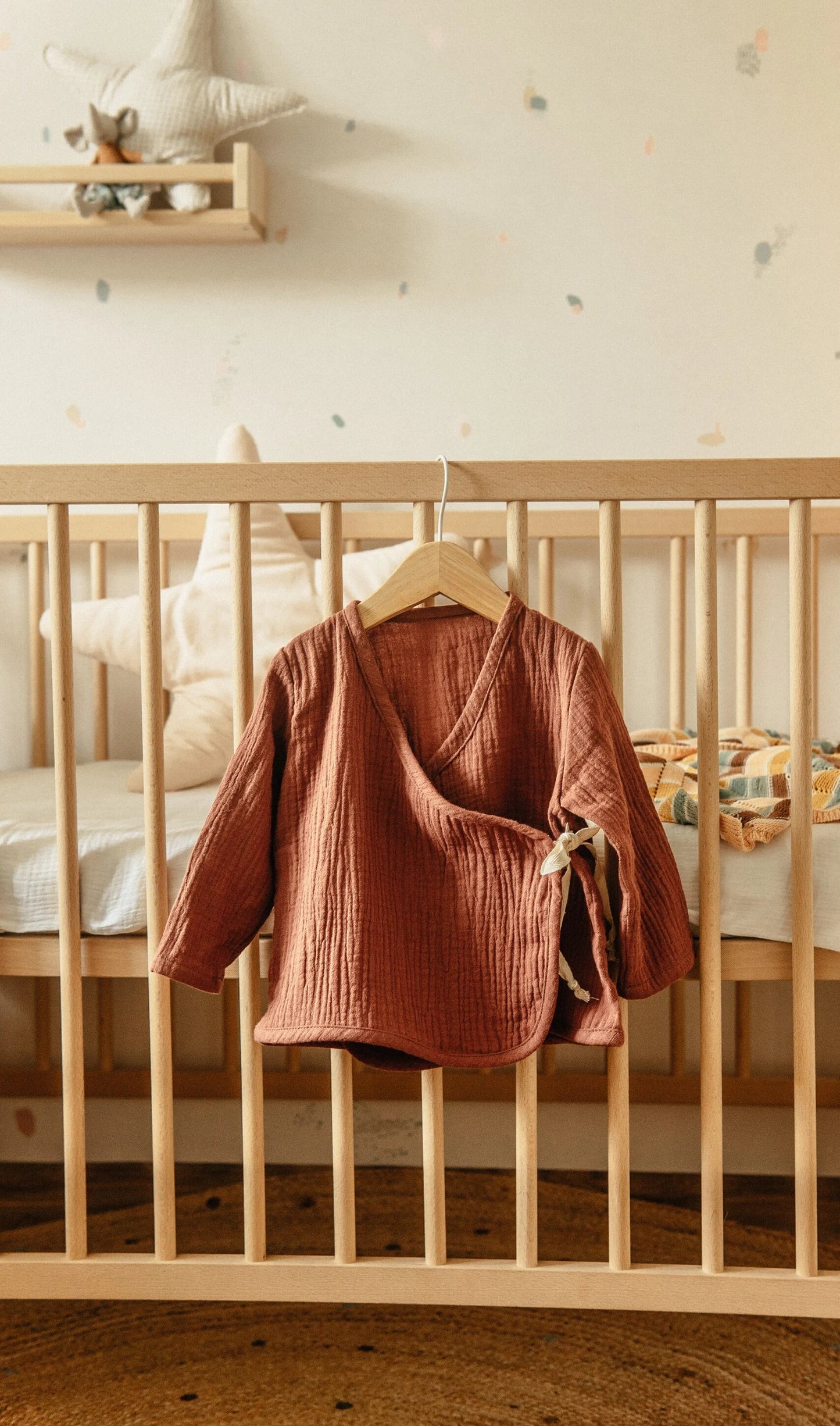 Comfortabele peuter outfit in warme tint bij houten babybed